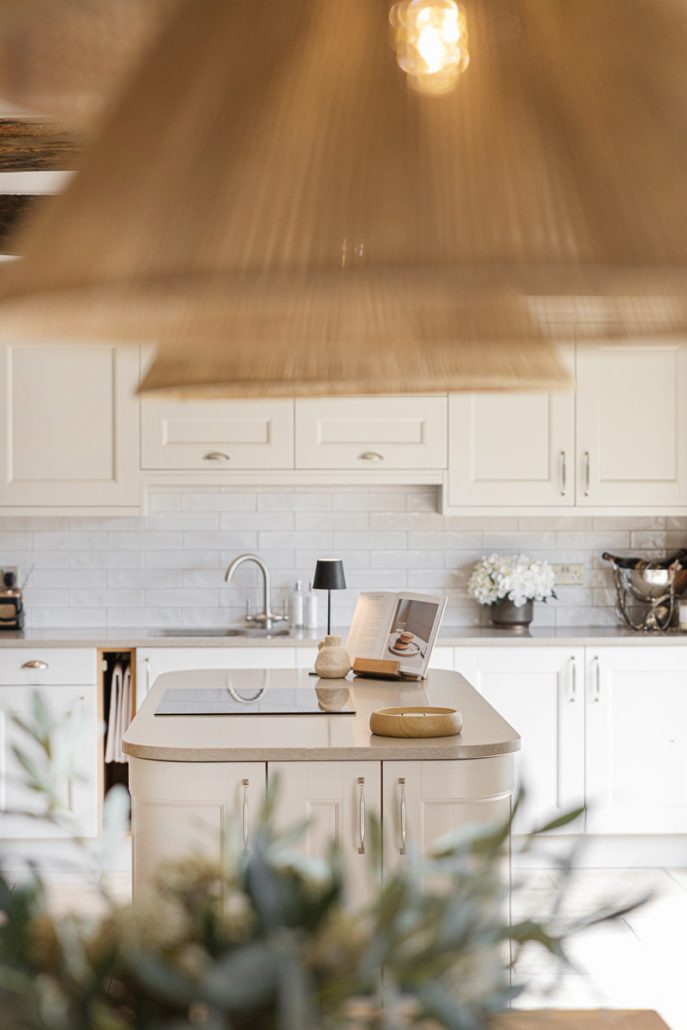 modern farmhouse kitchen with white cabinets, wooden beams, and pendant lights.