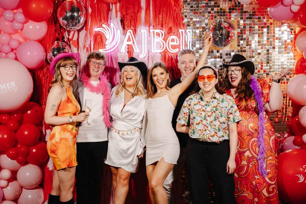 Guests posing at AJ Bell Summer Party photo backdrop captured by Awards Event Photographers Manchester