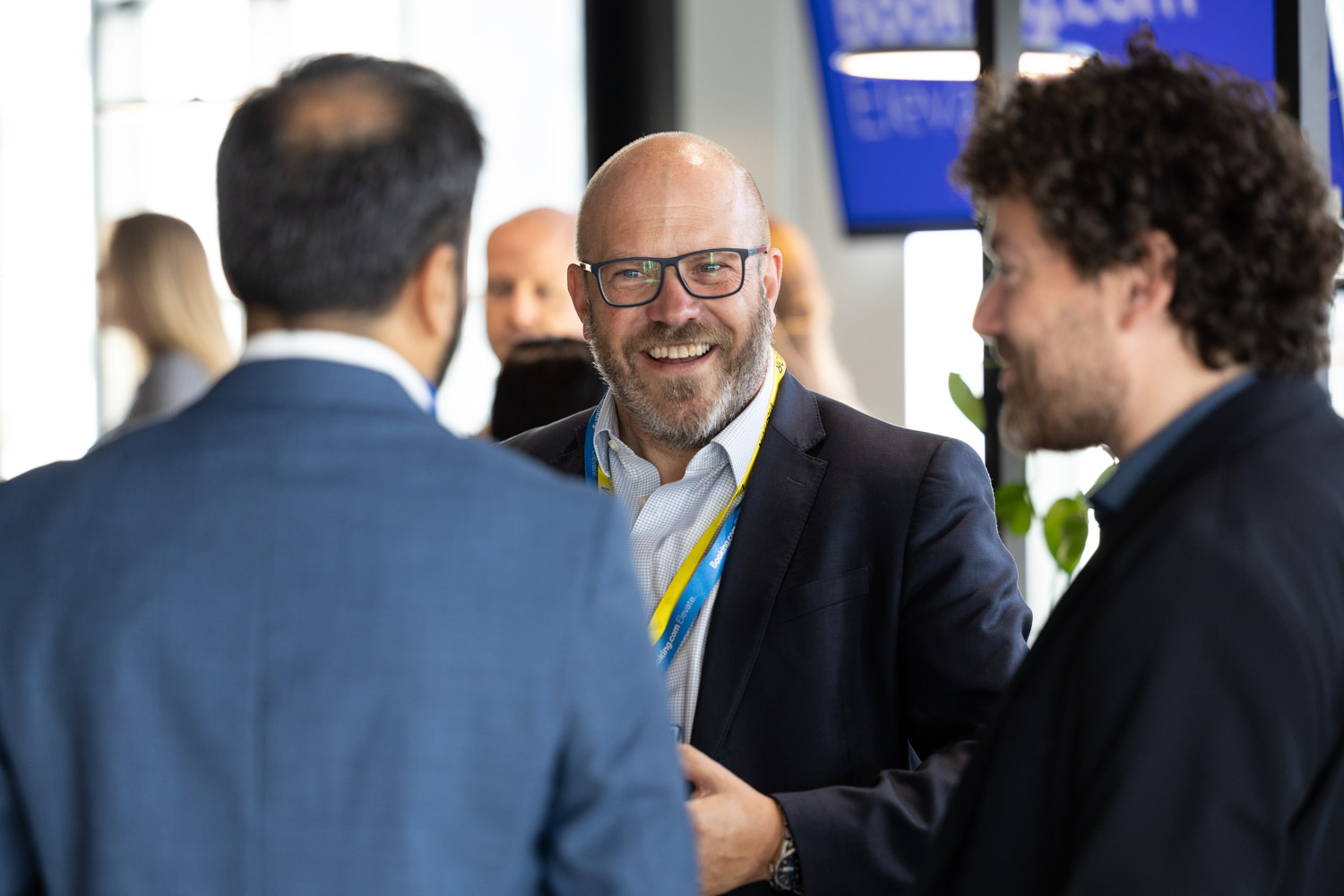 Guests networking and chatting in the Booking.com Manchester office café area during a corporate event.