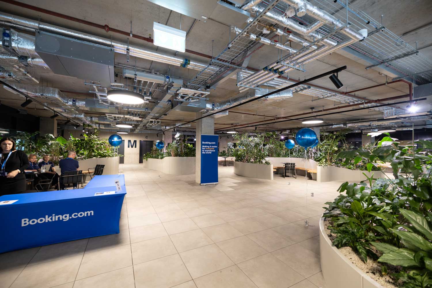 Guests networking and chatting in the Booking.com Manchester office café area during a corporate event.
