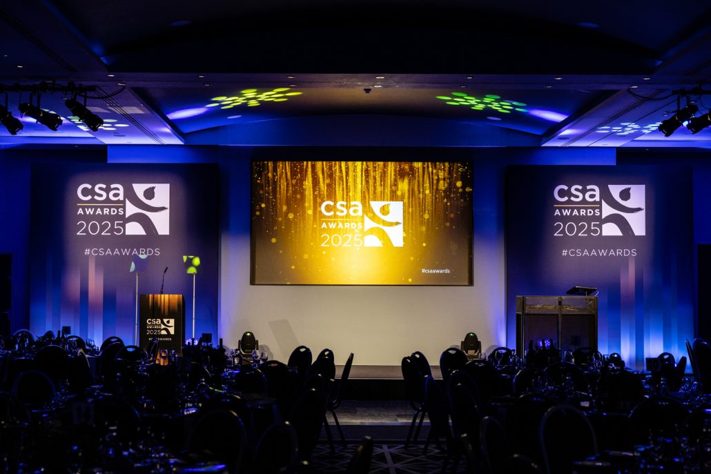 CSA Awards 2025 stage setup with gold screen and blue lighting, awards photography Manchester