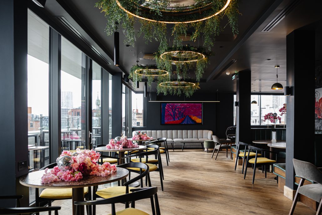 Rooftop summer party venue in Manchester with floral ceiling decor and city views, captured by Event Photographer Manchester
