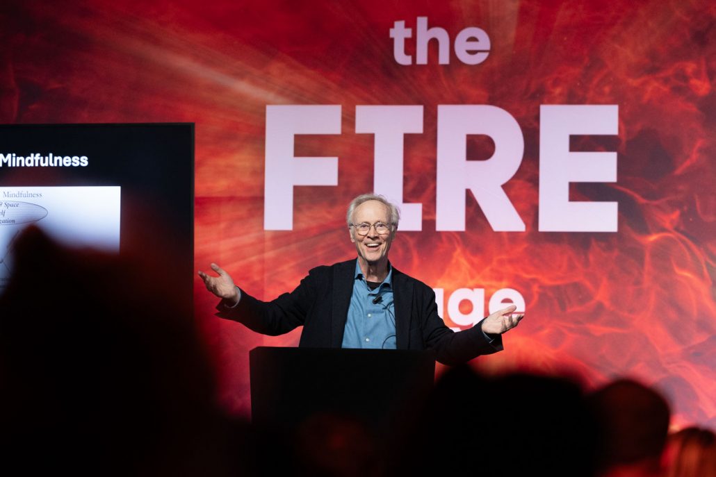 Speaker presenting on stage with fire-themed backdrop at Plannex Conference, captured by Conference Photographer Manchester